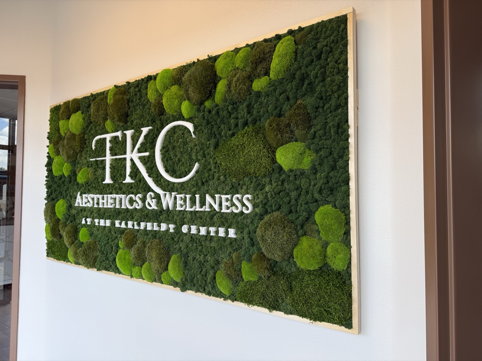 The TKC moss wall with integrated “TKC Aesthetics & Wellness” lettering